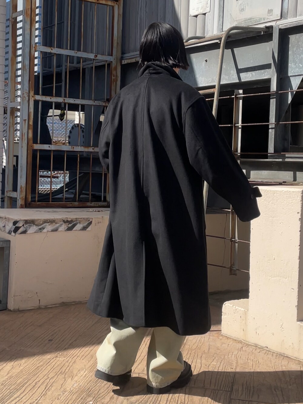 ブラック系のチェスターコート、ブラック系のテーラードジャケット、ブルー系のデニムパンツを着用したレディースの冬コーディネートの3枚目の写真