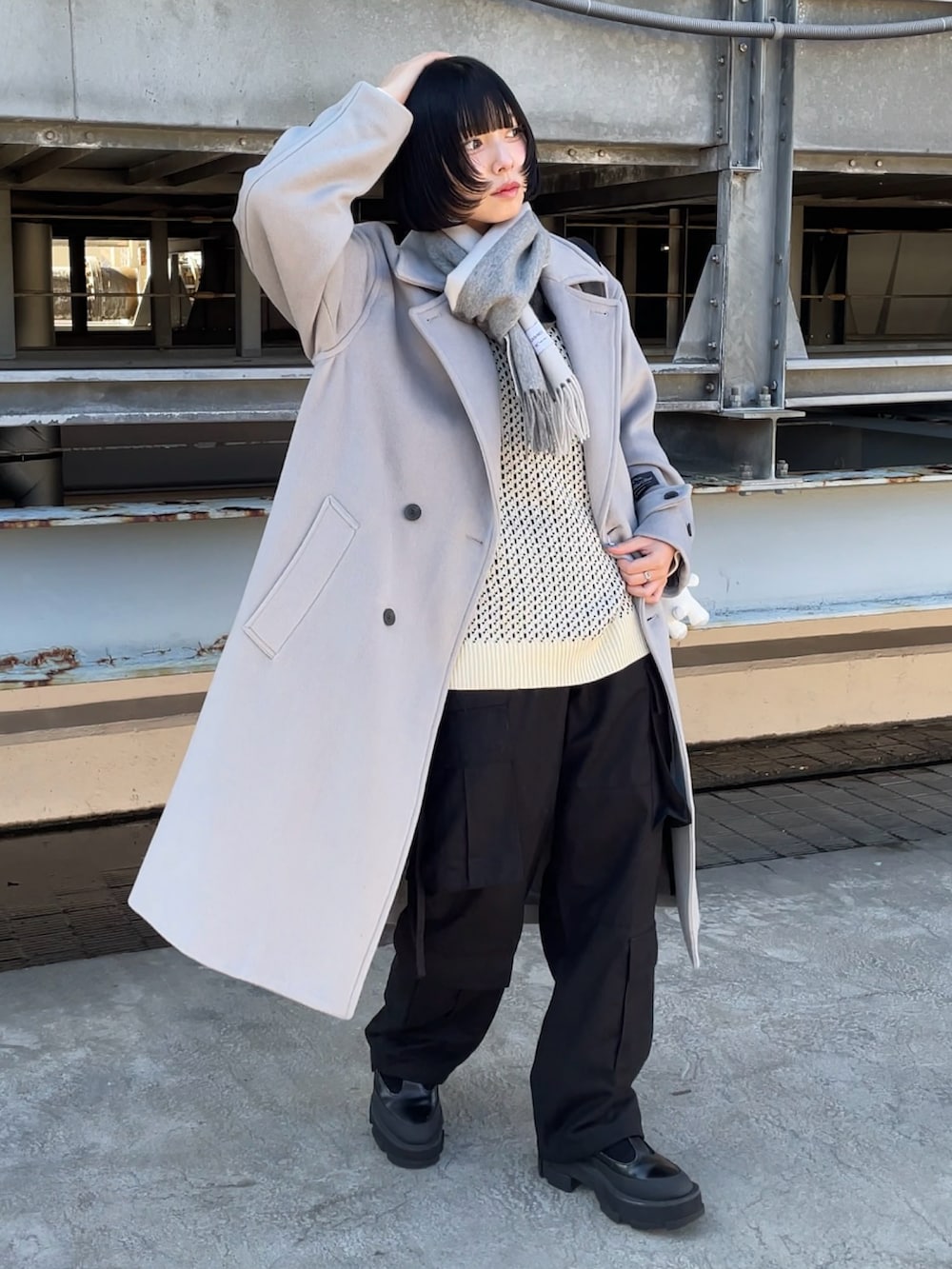 ブラック系のショルダーバッグ、グレー系のチェスターコート、ブラック系のカーゴパンツを着用したレディースの秋コーディネートの2枚目の写真