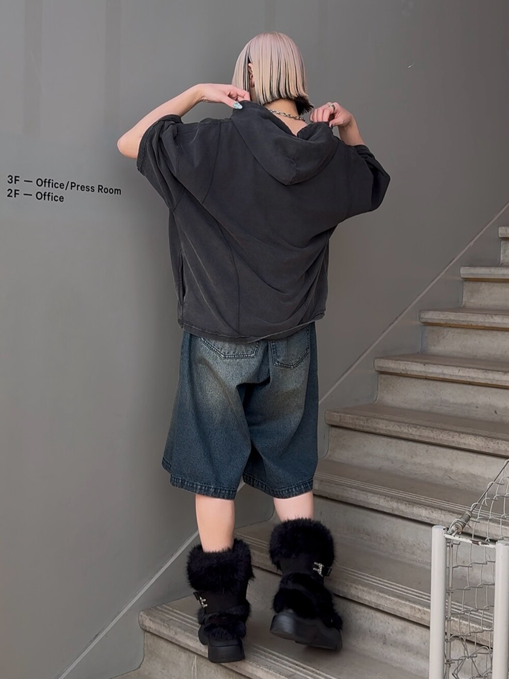 ブラック系のパーカー、ブルー系のデニムパンツを着用したレディースの春コーディネートの2枚目の写真