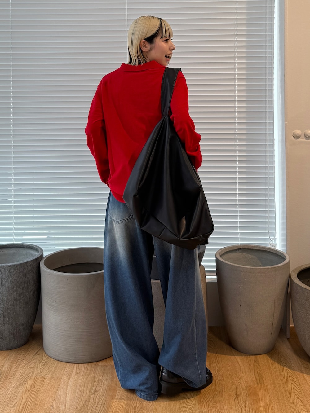 レッド系のニット/セーター、ブラック系のショルダーバッグ、ブルー系のデニムパンツを着用したレディースの夏コーディネートの2枚目の写真