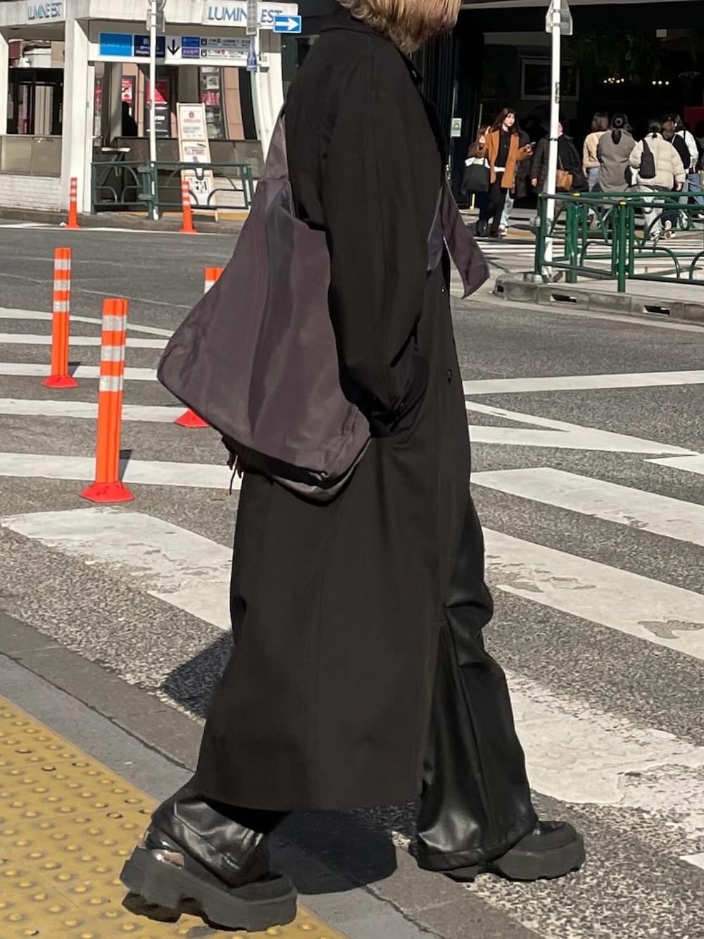 ブラック系のチェスターコート、グレー系のショルダーバッグ、ブラック系のカーゴパンツを着用したレディースの冬コーディネートの2枚目の写真