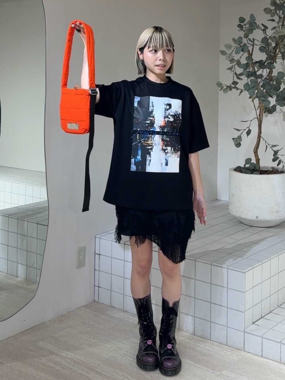 ブラック系のTシャツ/カットソー、オレンジ系のショルダーバッグ、ブラック系のブーツを着用したレディースの夏コーディネートの2枚目の写真