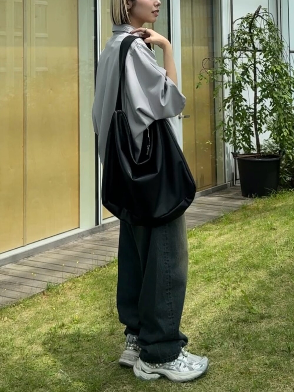 グレー系のシャツ/ブラウス、ブラック系のショルダーバッグ、ブルー系のデニムパンツを着用したレディースの春コーディネートの2枚目の写真