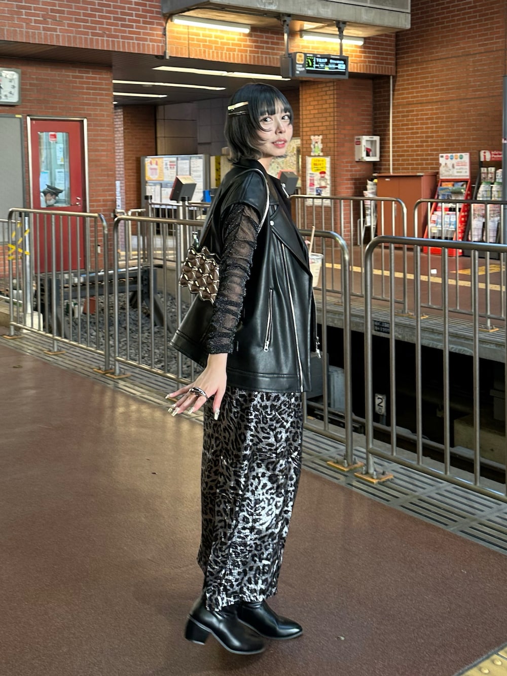 ブラック系のベスト、シルバー系のスカートを着用したレディースの春コーディネートの2枚目の写真