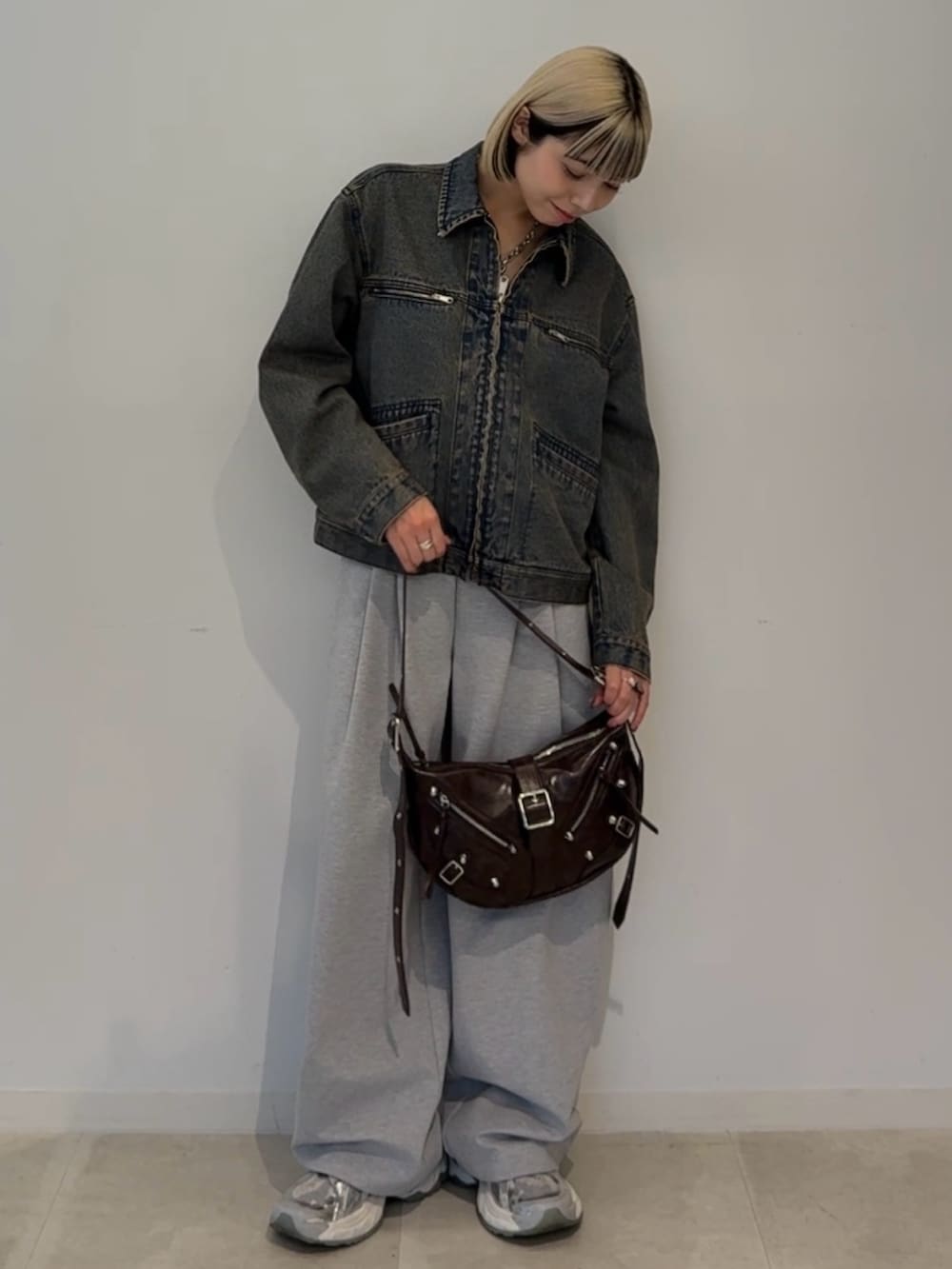 ブルー系のデニムジャケット、ブラウン系のショルダーバッグを着用したレディースの夏コーディネートの2枚目の写真