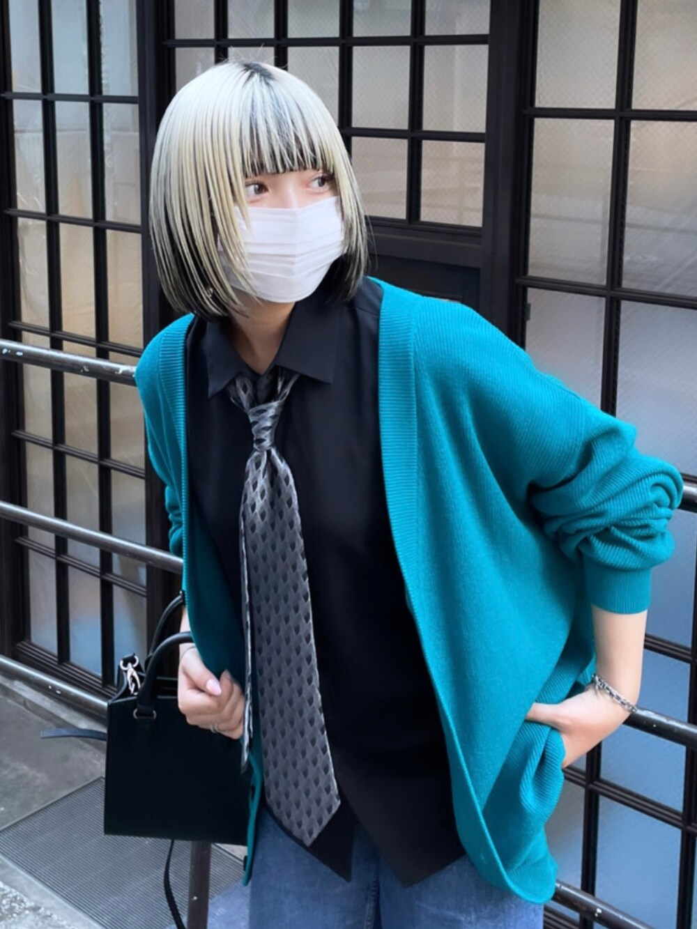 グリーン系のカーディガン/ボレロ、ブラック系のネクタイ、ブラック系のショルダーバッグを着用したレディースの秋コーディネートの2枚目の写真