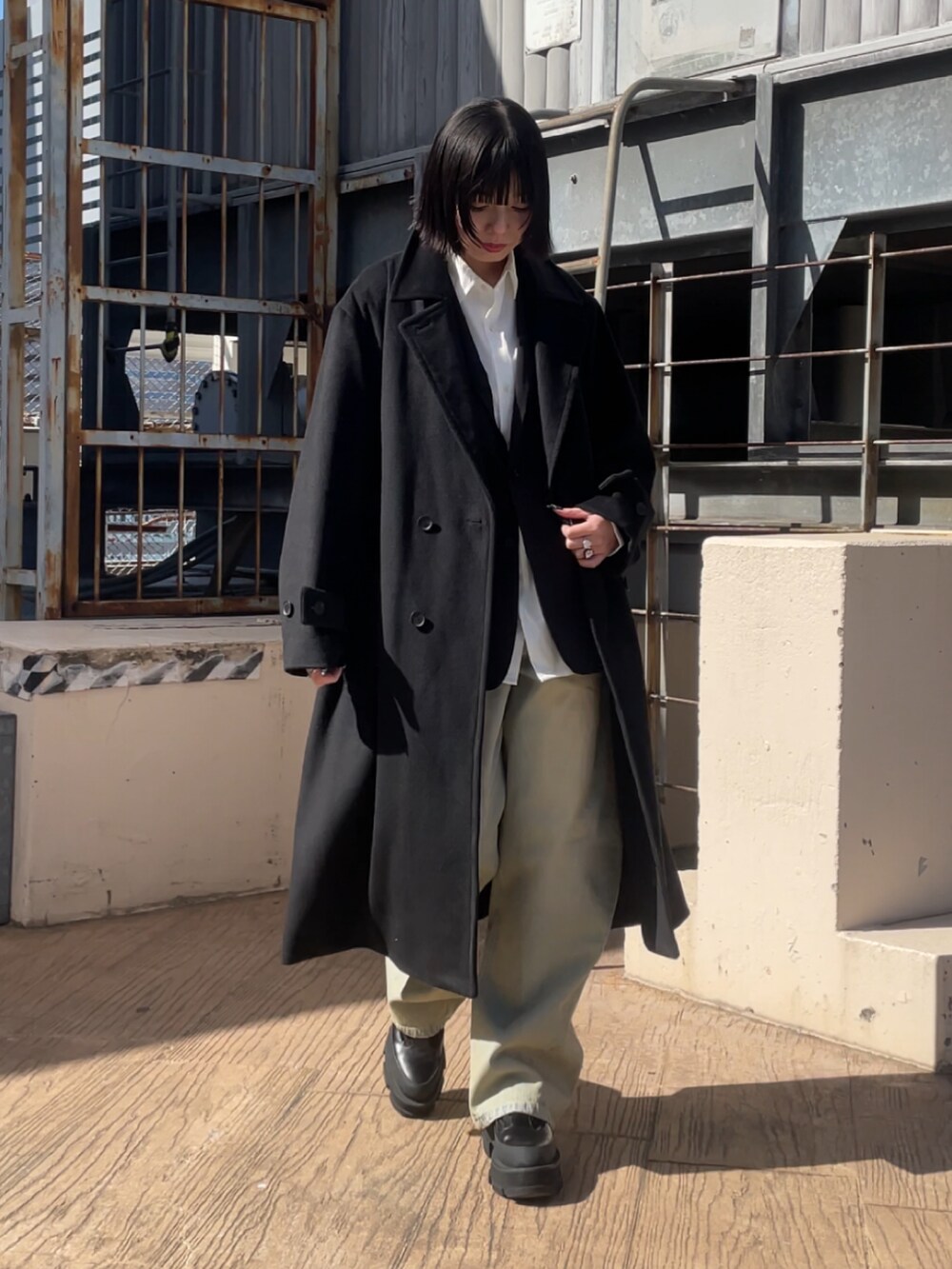 ブラック系のチェスターコート、ブラック系のテーラードジャケット、ブルー系のデニムパンツを着用したレディースの冬コーディネートの2枚目の写真