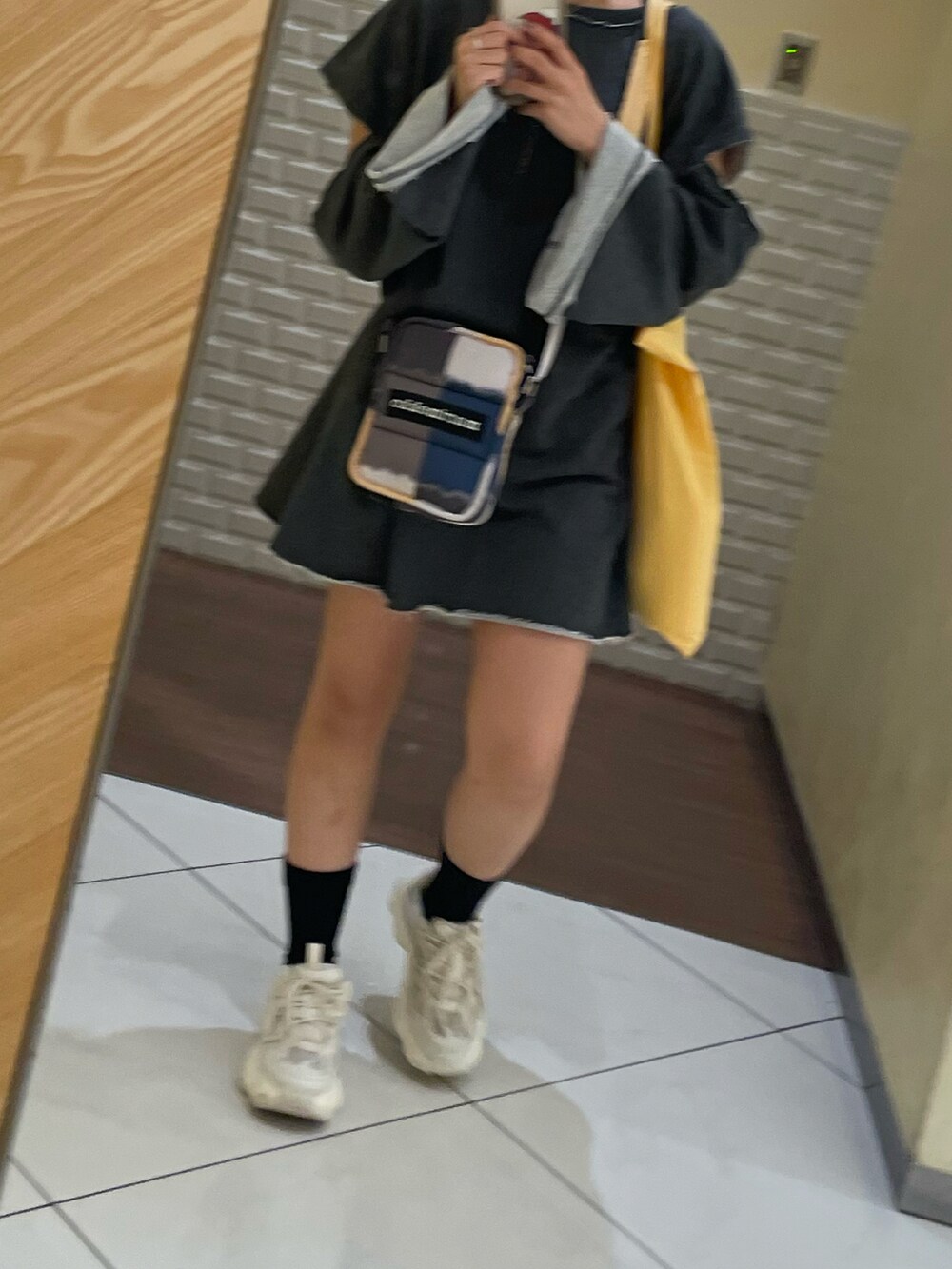 ホワイト系のスニーカー、ブラック系のショルダーバッグ、グレー系のスウェットを着用したレディースの秋コーディネートの2枚目の写真