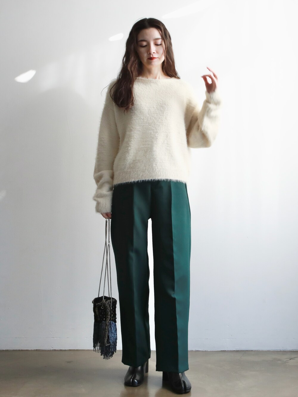 ブラウン系のハンドバッグ、ホワイト系のニット/セーター、ゴールド系のバレエシューズを着用したレディースの冬コーディネートの5枚目の写真