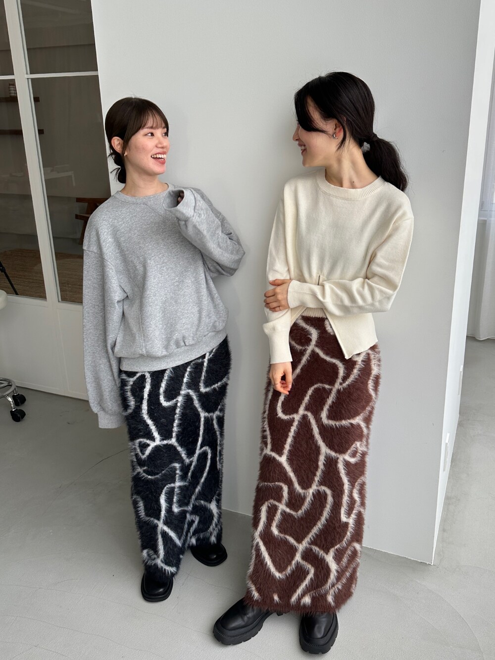 ホワイト系のニット/セーター、ブラウン系のスカート、ブラック系のスカートを着用したレディースの冬コーディネートの4枚目の写真