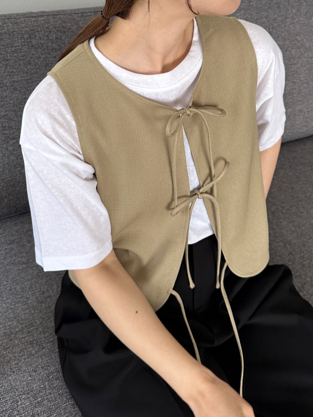 ベージュ系のベスト、ホワイト系のTシャツ/カットソー、ブラック系のサンダルを着用したレディースの夏コーディネートの3枚目の写真