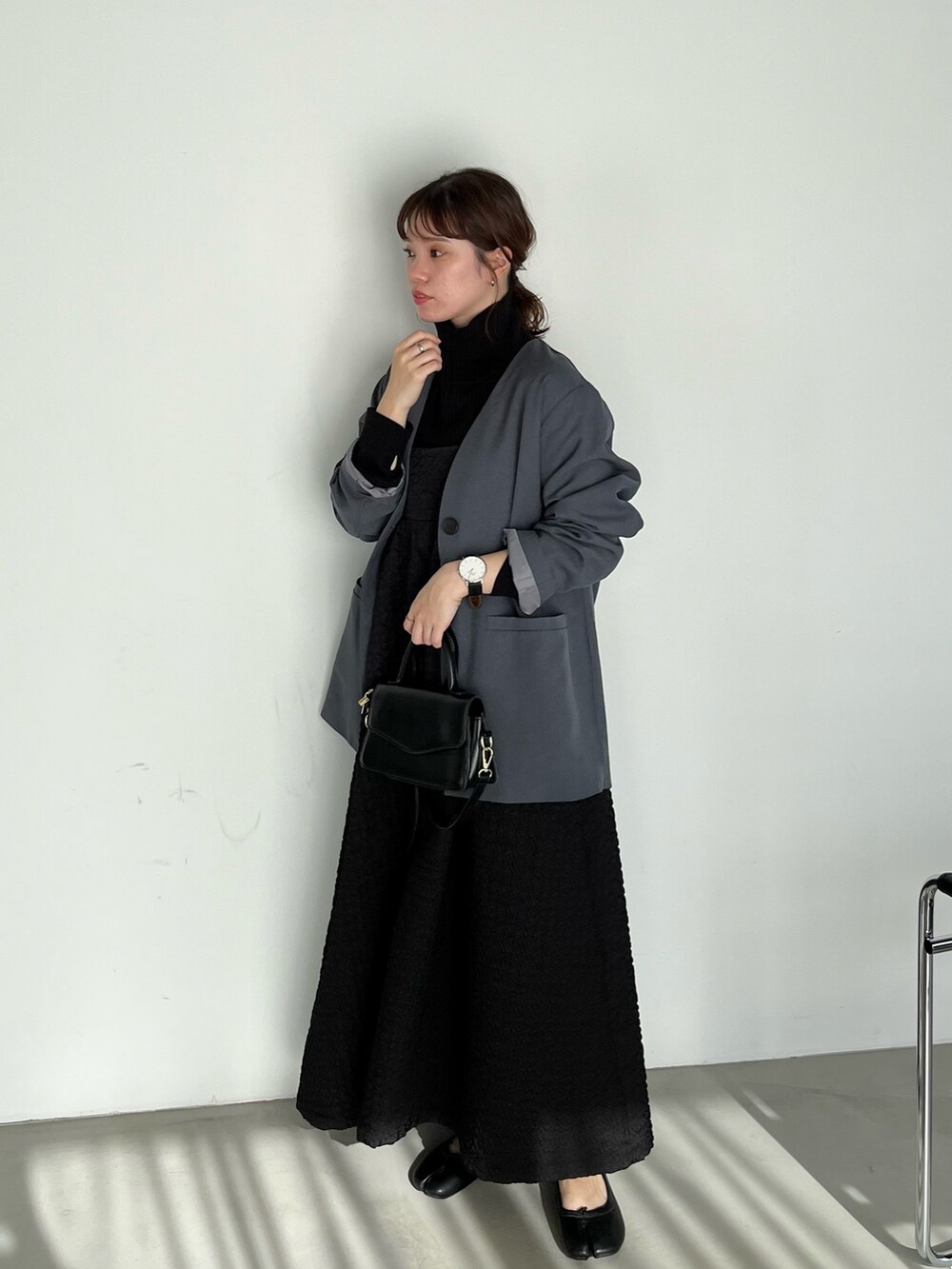 ブラック系のワンピース、グレー系のノーカラージャケット、ブラック系のニット/セーターを着用したレディースの冬コーディネートの2枚目の写真