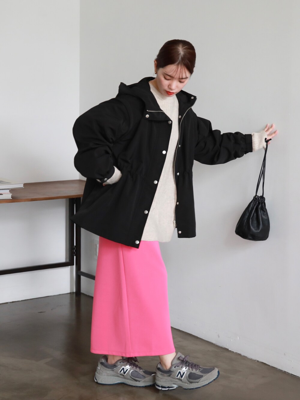 ブラック系のマウンテンパーカー、ブラック系のハンドバッグ、ピンク系のスカートを着用したレディースの秋コーディネートの2枚目の写真