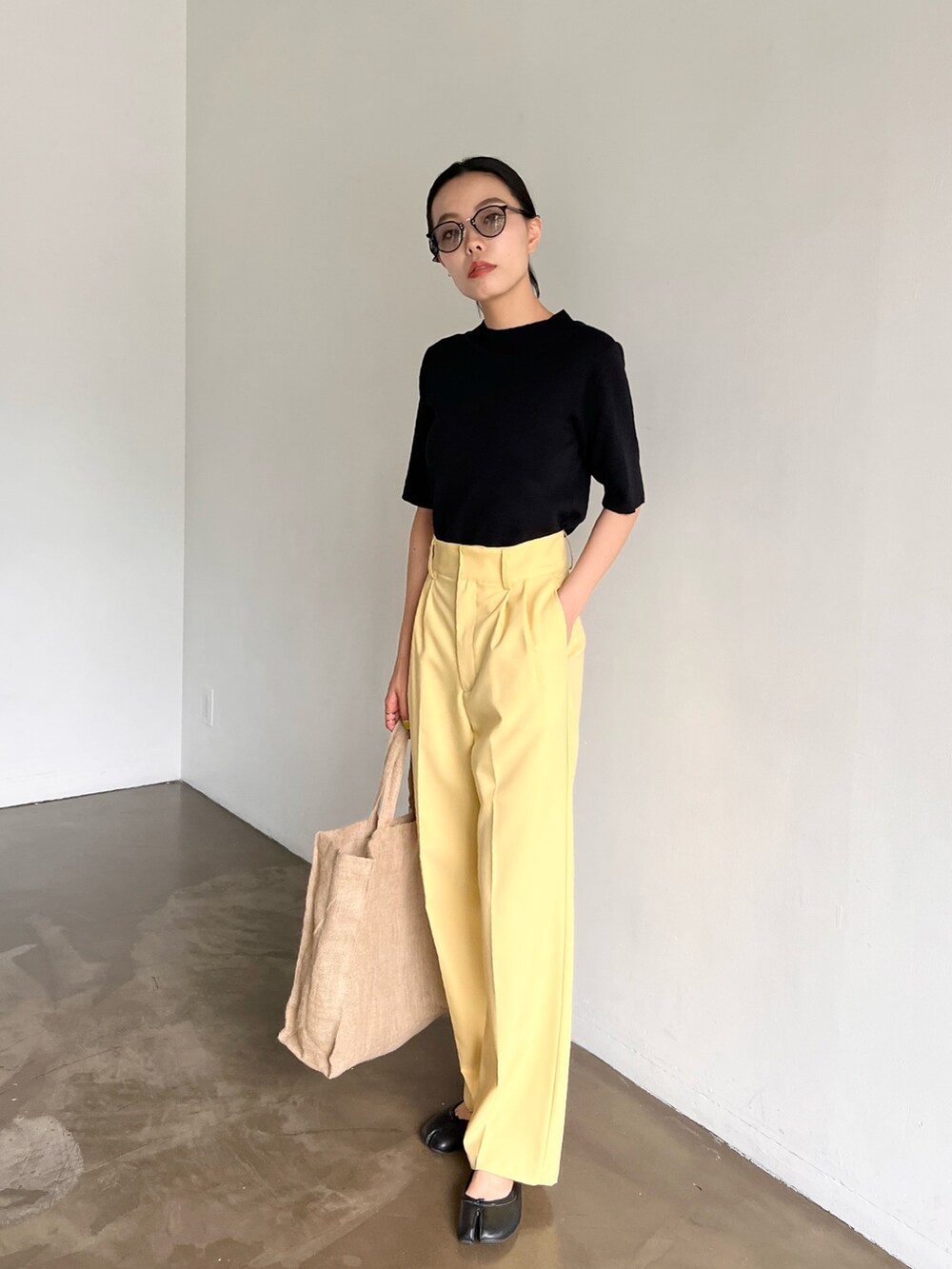 イエロー系のスラックス、パープル系のトートバッグ、ブラック系のパンプスを着用したレディースの夏コーディネートの2枚目の写真