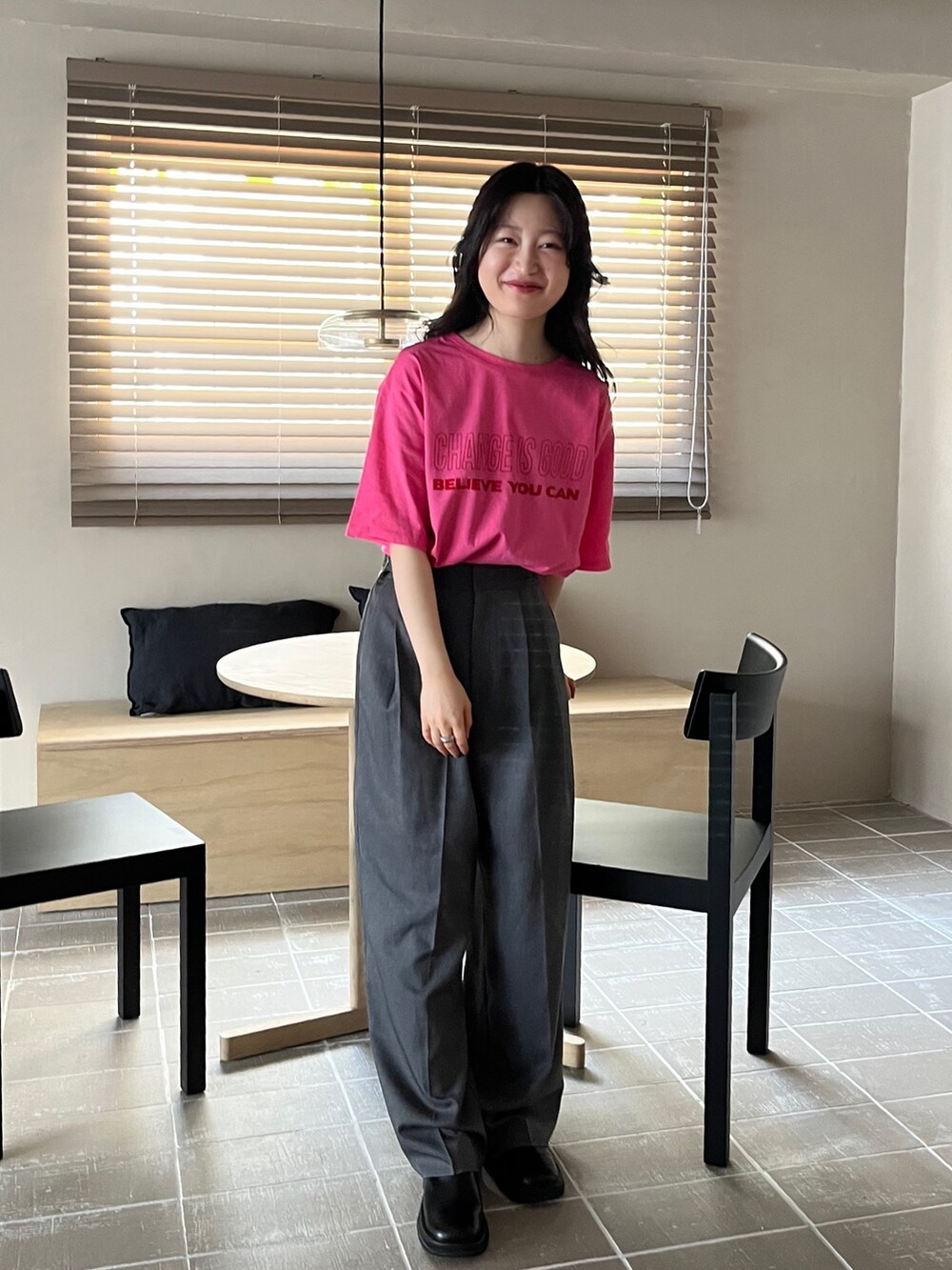 グレー系のスラックス、ピンク系のTシャツ/カットソー、ブラック系のスリッポンを着用したレディースの夏コーディネートの2枚目の写真