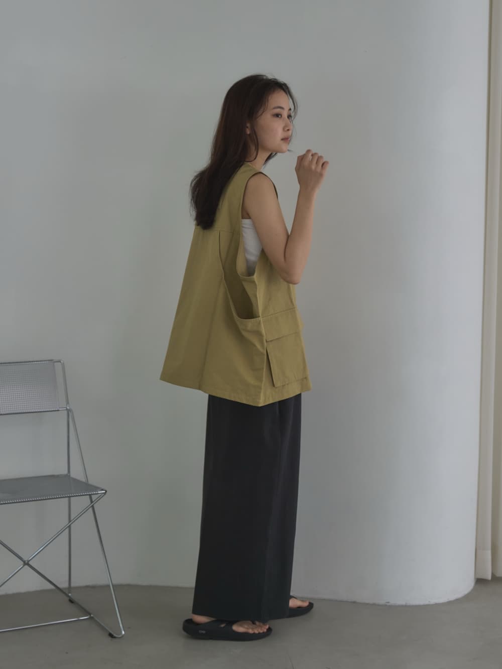 ホワイト系のキャミソール、ベージュ系のベスト、ブラック系のサンダルを着用したレディースの夏コーディネートの3枚目の写真