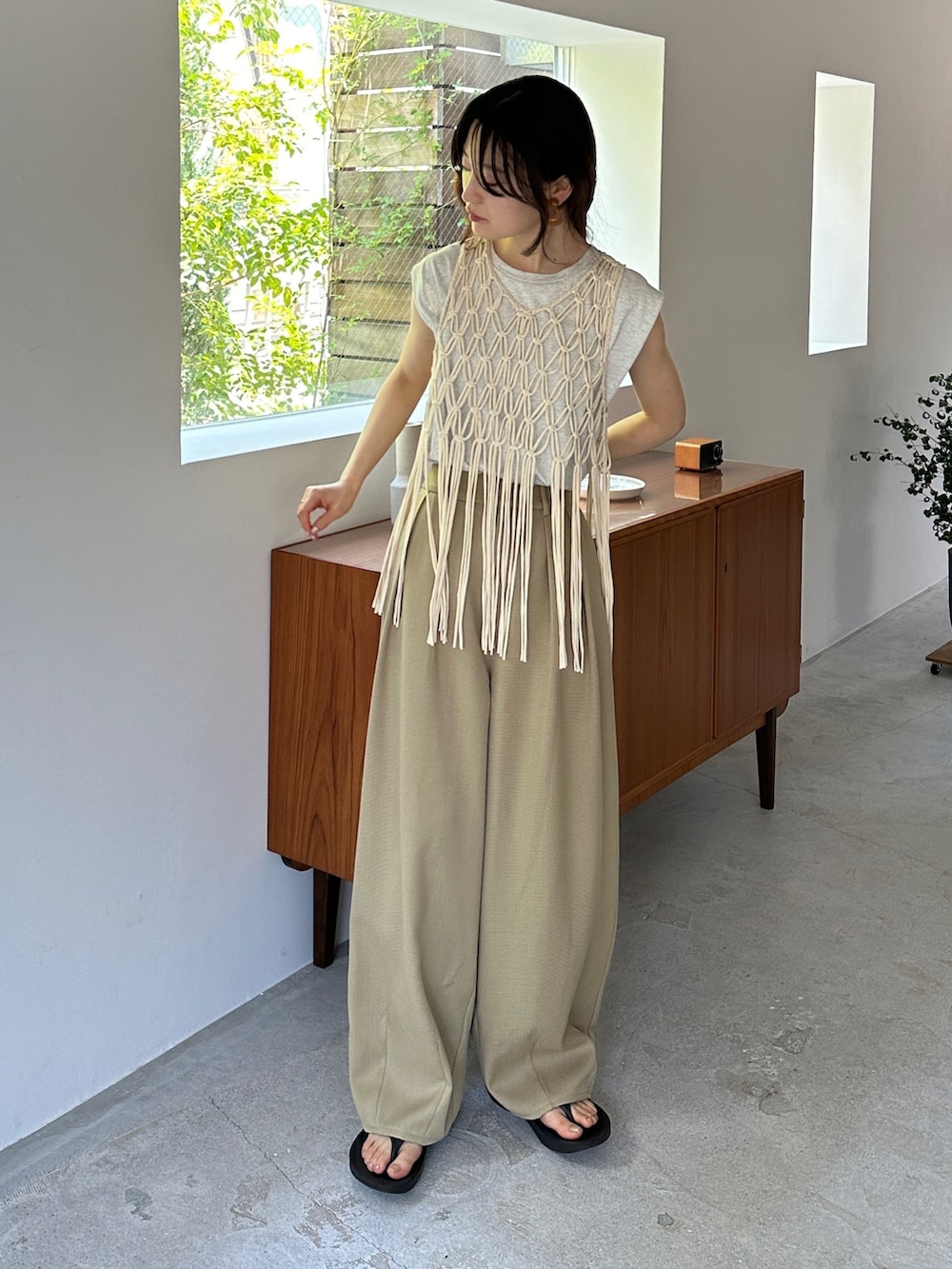 ホワイト系のベスト、ベージュ系のタンクトップ、ベージュ系のスラックスを着用したレディースの夏コーディネートの2枚目の写真