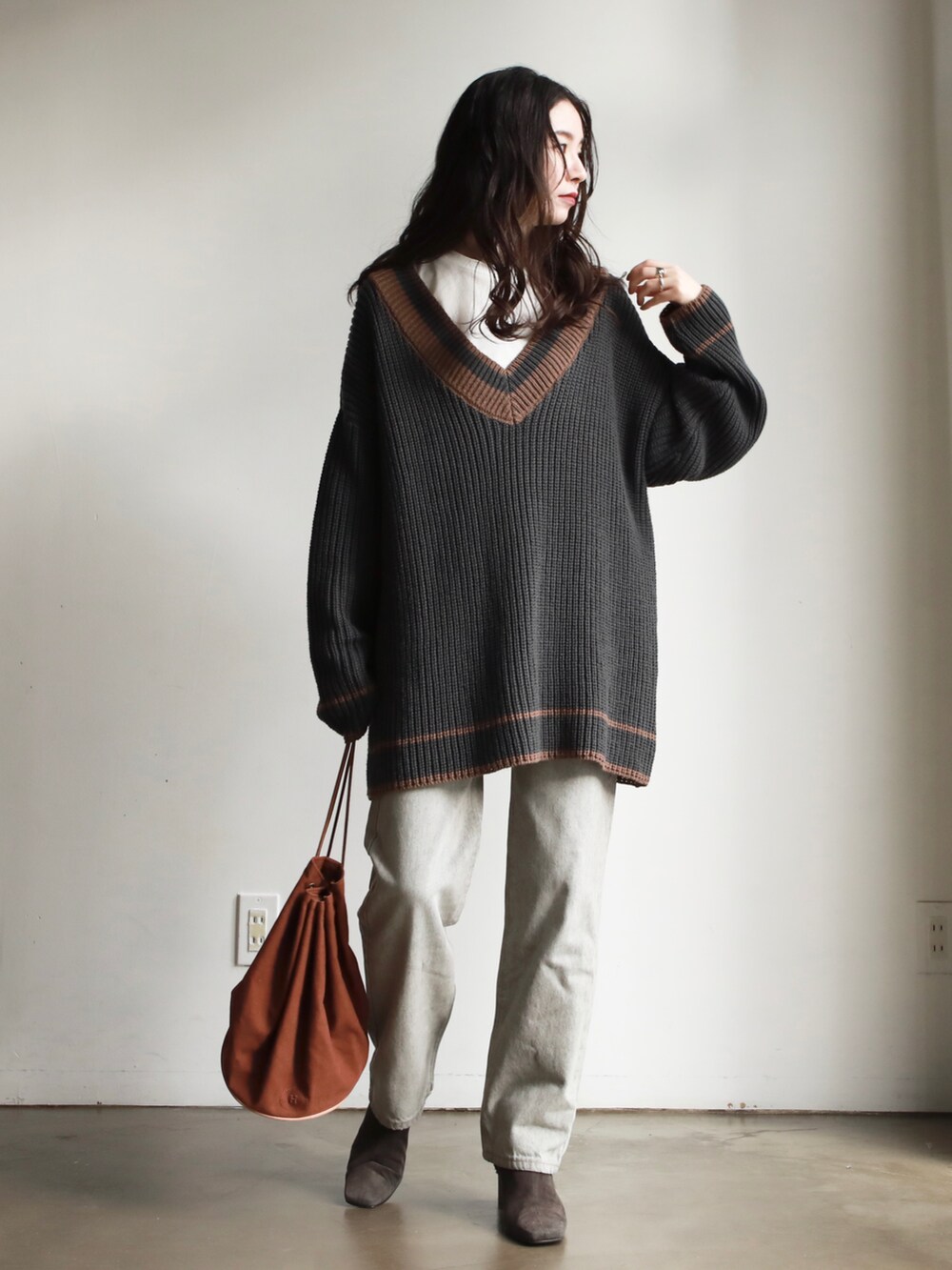 ブラック系のニット/セーター、ホワイト系のシャツ/ブラウス、ブラウン系のハンドバッグを着用したレディースの冬コーディネートの5枚目の写真