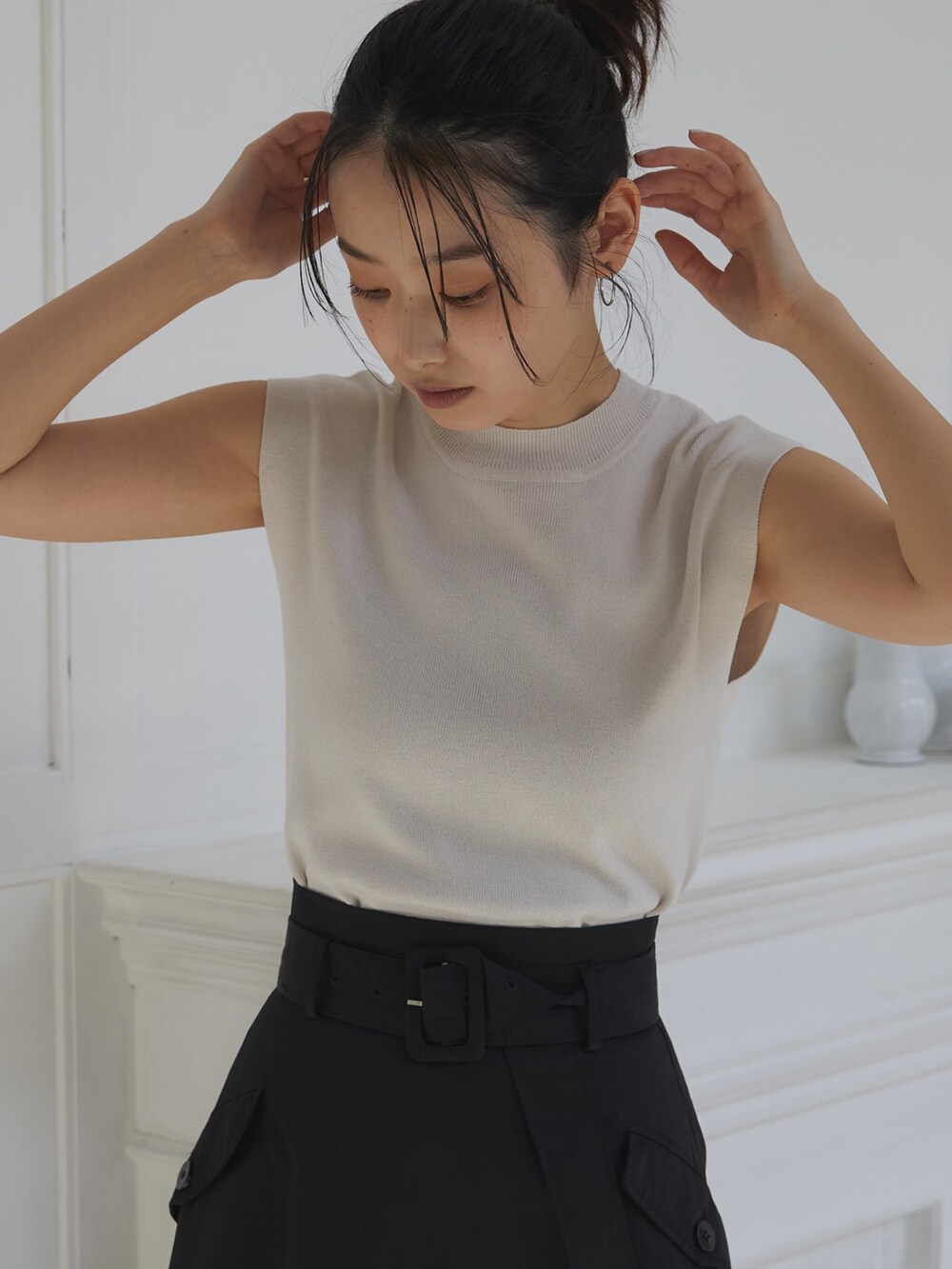 ブラック系のスカート、ホワイト系のニット/セーター、ブラック系のスリッポンを着用したレディースの夏コーディネートの4枚目の写真