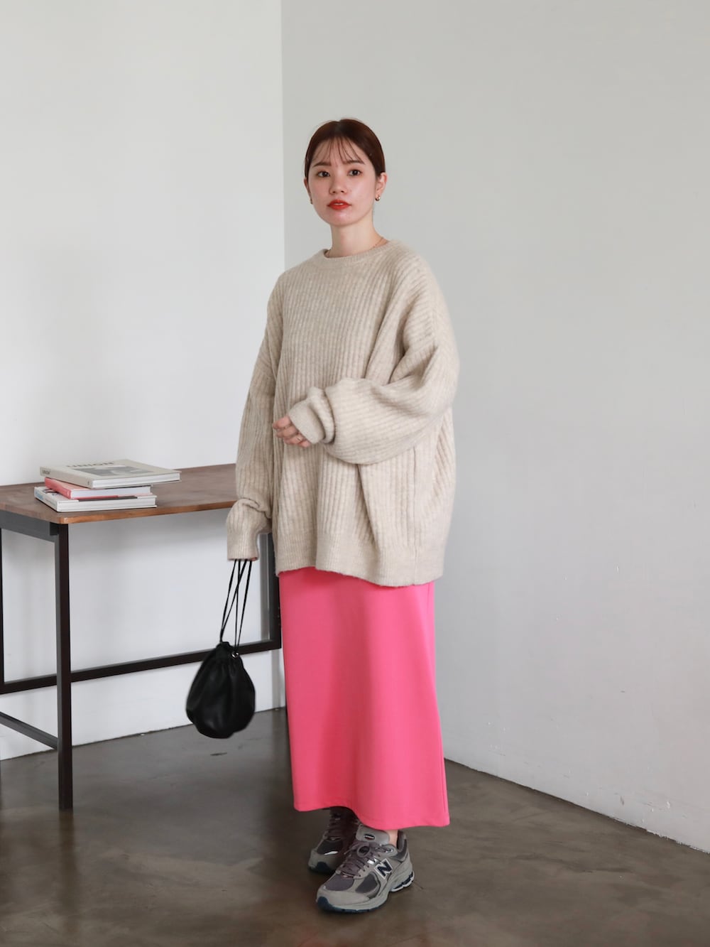 ブラック系のマウンテンパーカー、ブラック系のハンドバッグ、ピンク系のスカートを着用したレディースの秋コーディネートの3枚目の写真