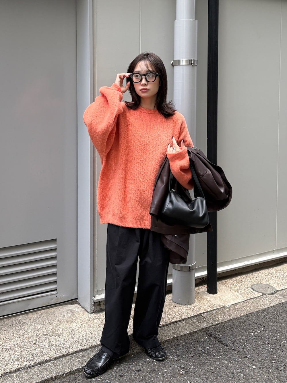 ブラウン系のカバーオール、オレンジ系のニット/セーター、ブラック系のショルダーバッグを着用したレディースの冬コーディネートの4枚目の写真