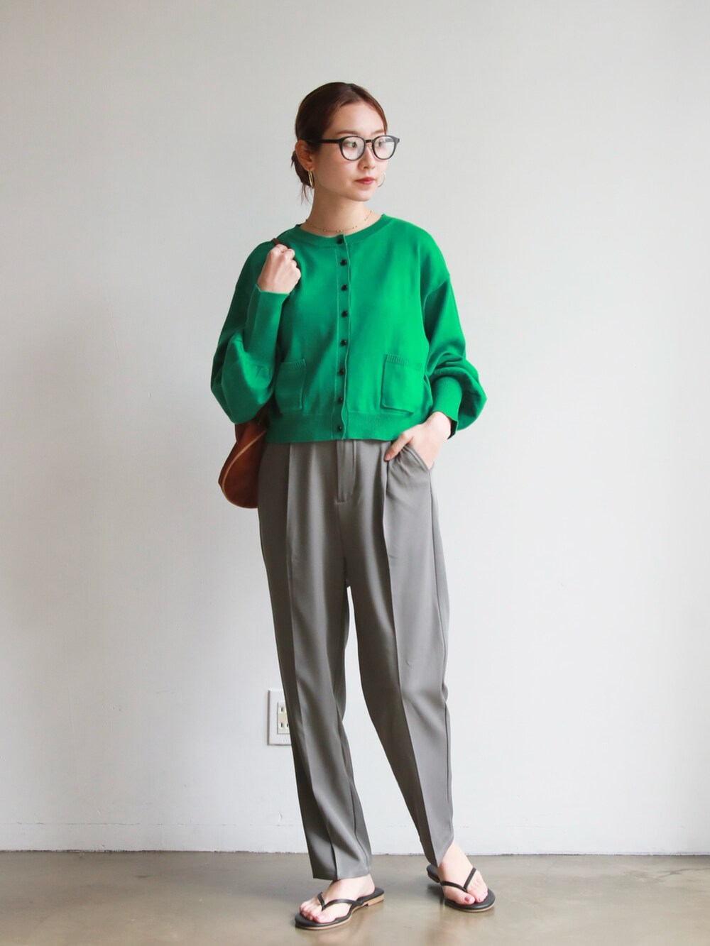 グレー系のスラックス、グリーン系のカーディガン/ボレロ、ホワイト系のセットアップを着用したレディースの春コーディネートの4枚目の写真