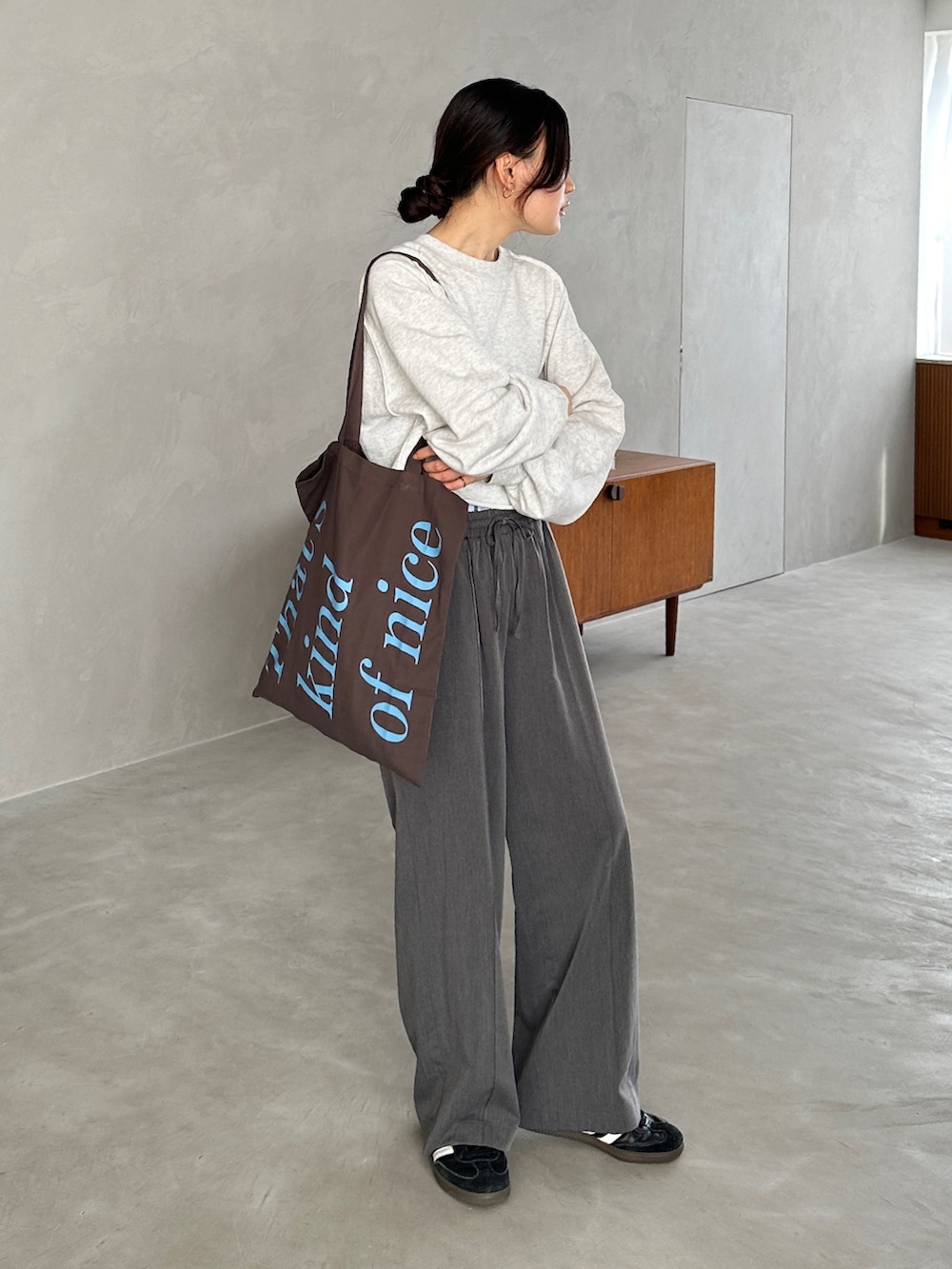 グレー系のスウェット、グレー系のスラックス、ブラック系のスニーカーを着用したレディースの秋コーディネートの4枚目の写真