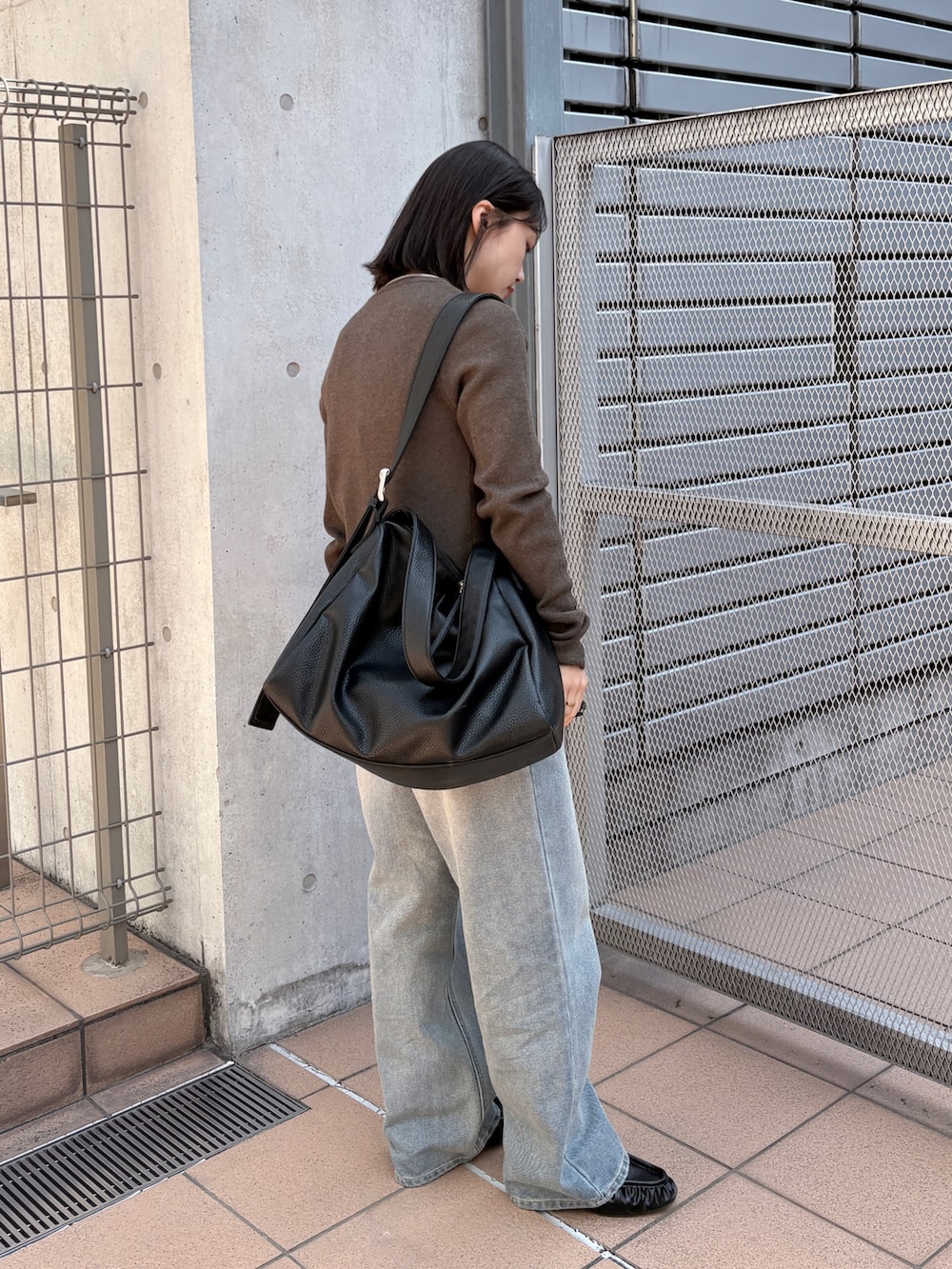 ブラウン系のカーディガン/ボレロ、ブルー系のデニムパンツ、ブラック系のショルダーバッグを着用したレディースの春コーディネートの2枚目の写真