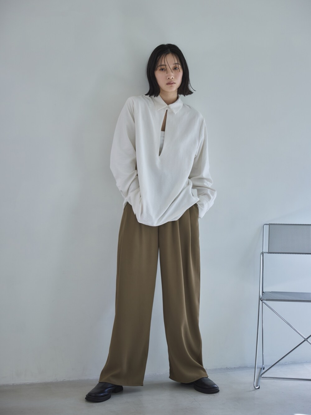 ホワイト系のシャツ/ブラウス、ベージュ系のスラックス、ブラック系のスリッポンを着用したレディースの春コーディネートの2枚目の写真