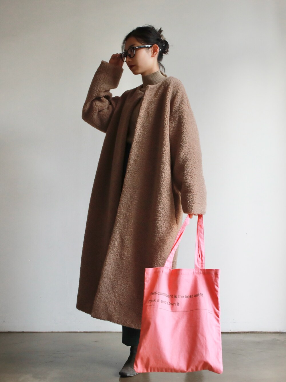 ピンク系のトートバッグ、ベージュ系のニット/セーター、グレー系のブーツを着用したレディースの秋コーディネートの2枚目の写真