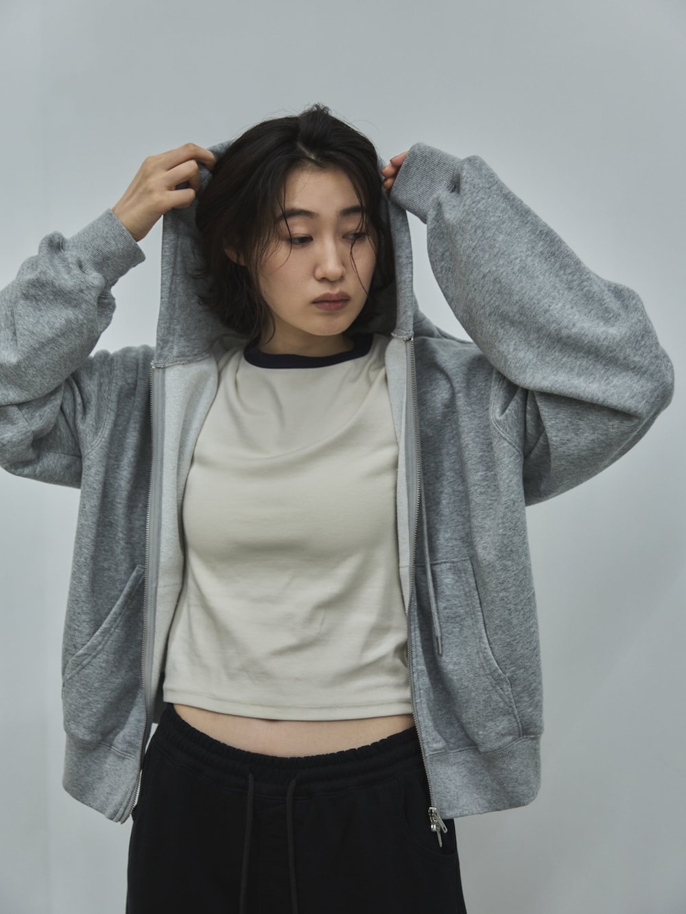 グレー系のパーカー、ホワイト系のTシャツ/カットソー、ブラック系のデニムパンツを着用したレディースの秋コーディネートの3枚目の写真