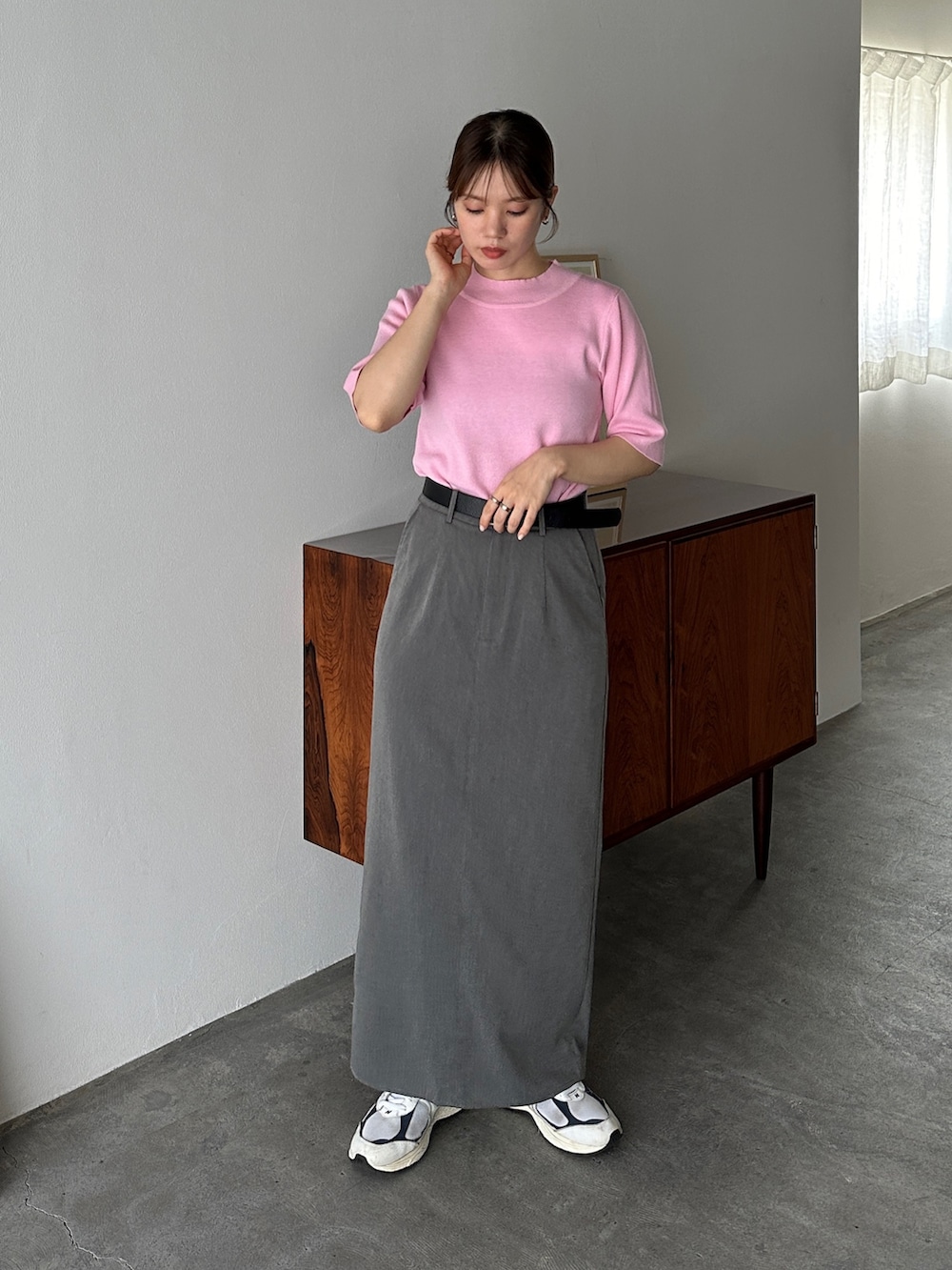 ピンク系のニット/セーター、グレー系のスカート、ホワイト系のスニーカーを着用したレディースの夏コーディネートの2枚目の写真