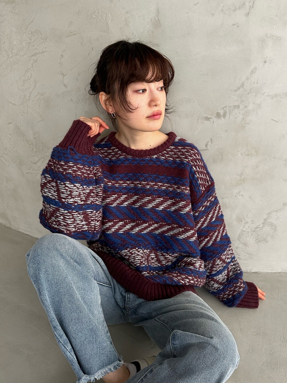 レッド系のニット/セーター、ブルー系のデニムパンツ、ホワイト系のスニーカーを着用したレディースの冬コーディネートの3枚目の写真