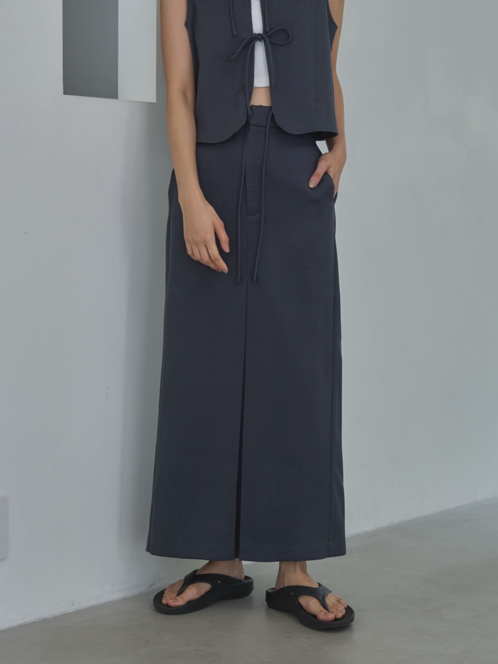 グレー系のベスト、ホワイト系のキャミソール、グレー系のスカートを着用したレディースの夏コーディネートの3枚目の写真