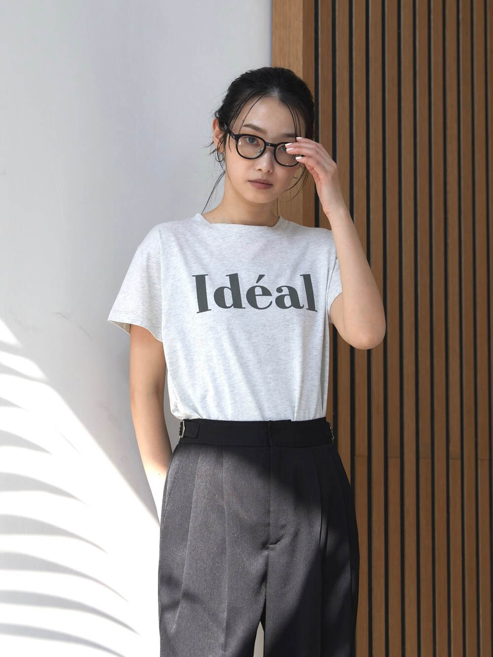 ブラック系のスラックス、ホワイト系のスニーカー、ベージュ系のTシャツ/カットソーを着用したレディースの夏コーディネートの3枚目の写真