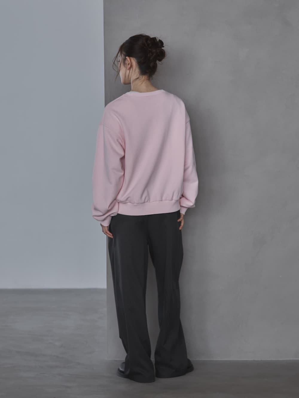 ピンク系のスウェット、グレー系のスラックス、ブラック系のその他シューズを着用したレディースの春コーディネートの2枚目の写真