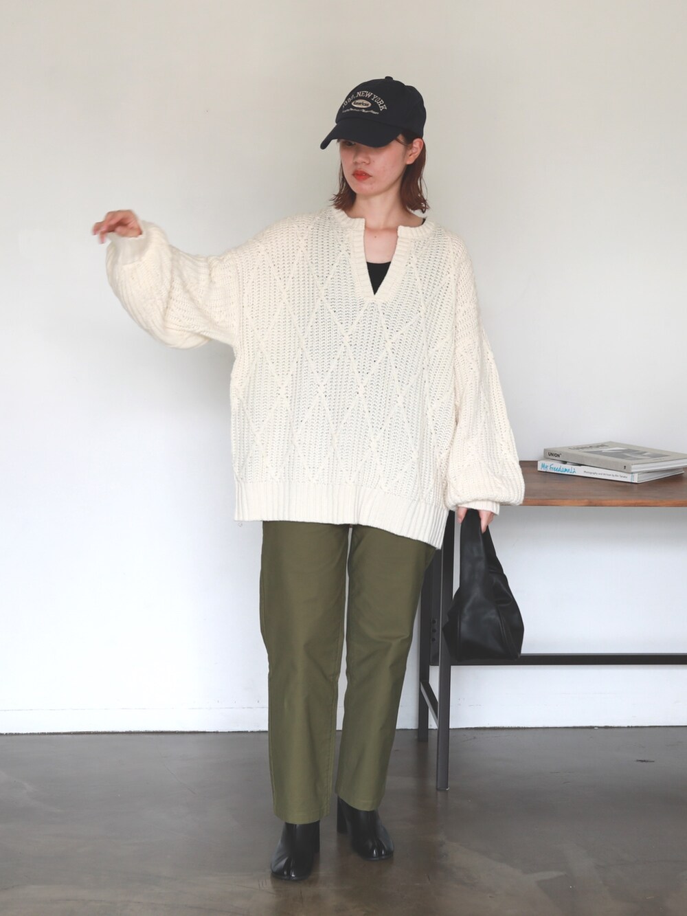ホワイト系のニット/セーター、グリーン系のチノパンツ、ブラック系のハンドバッグを着用したレディースの冬コーディネートの2枚目の写真