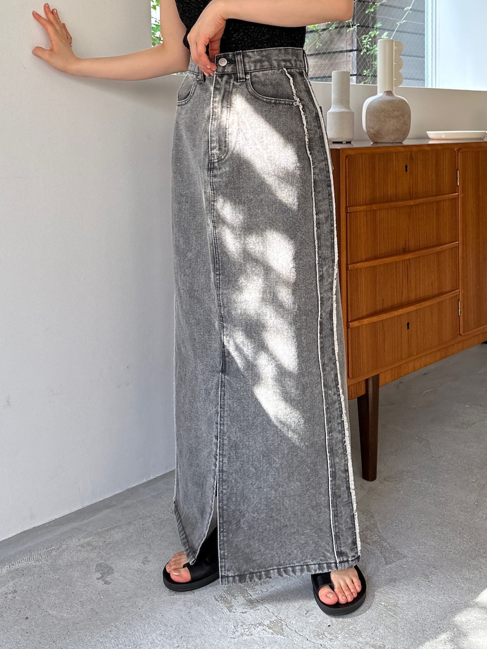 ブラック系のニット/セーター、グレー系のデニムスカート、ブラック系のサンダルを着用したレディースの夏コーディネートの3枚目の写真