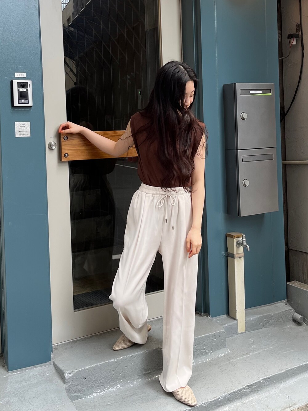 ブルー系のニット/セーター、ブラック系のスラックス、ホワイト系のスラックスを着用したレディースの春コーディネートの3枚目の写真