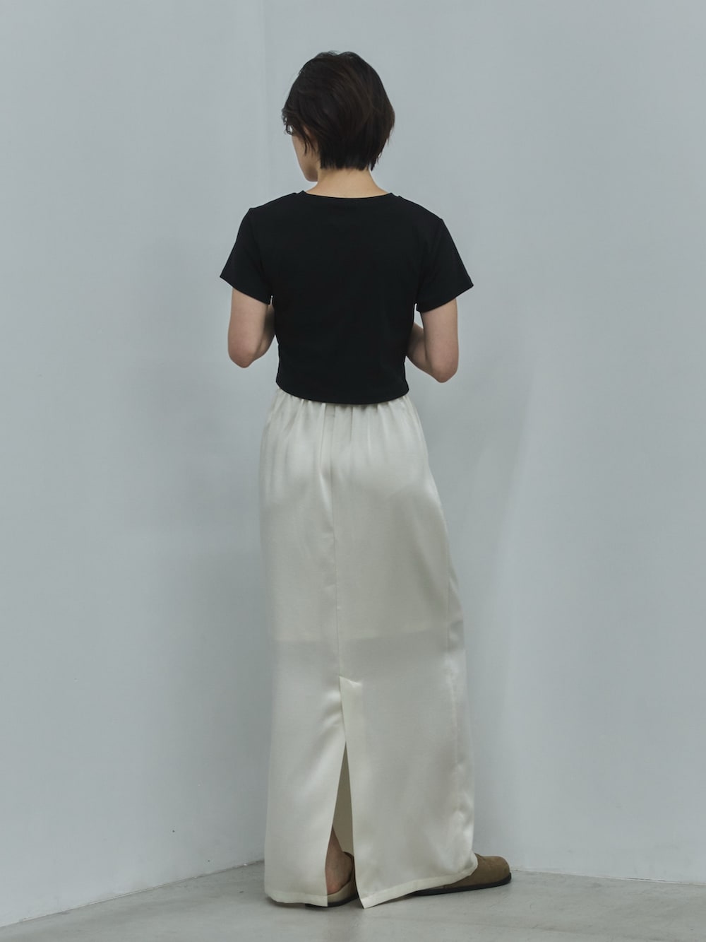 ブラック系のTシャツ/カットソー、ホワイト系のスカート、ブラック系のサンダルを着用したレディースの夏コーディネートの3枚目の写真
