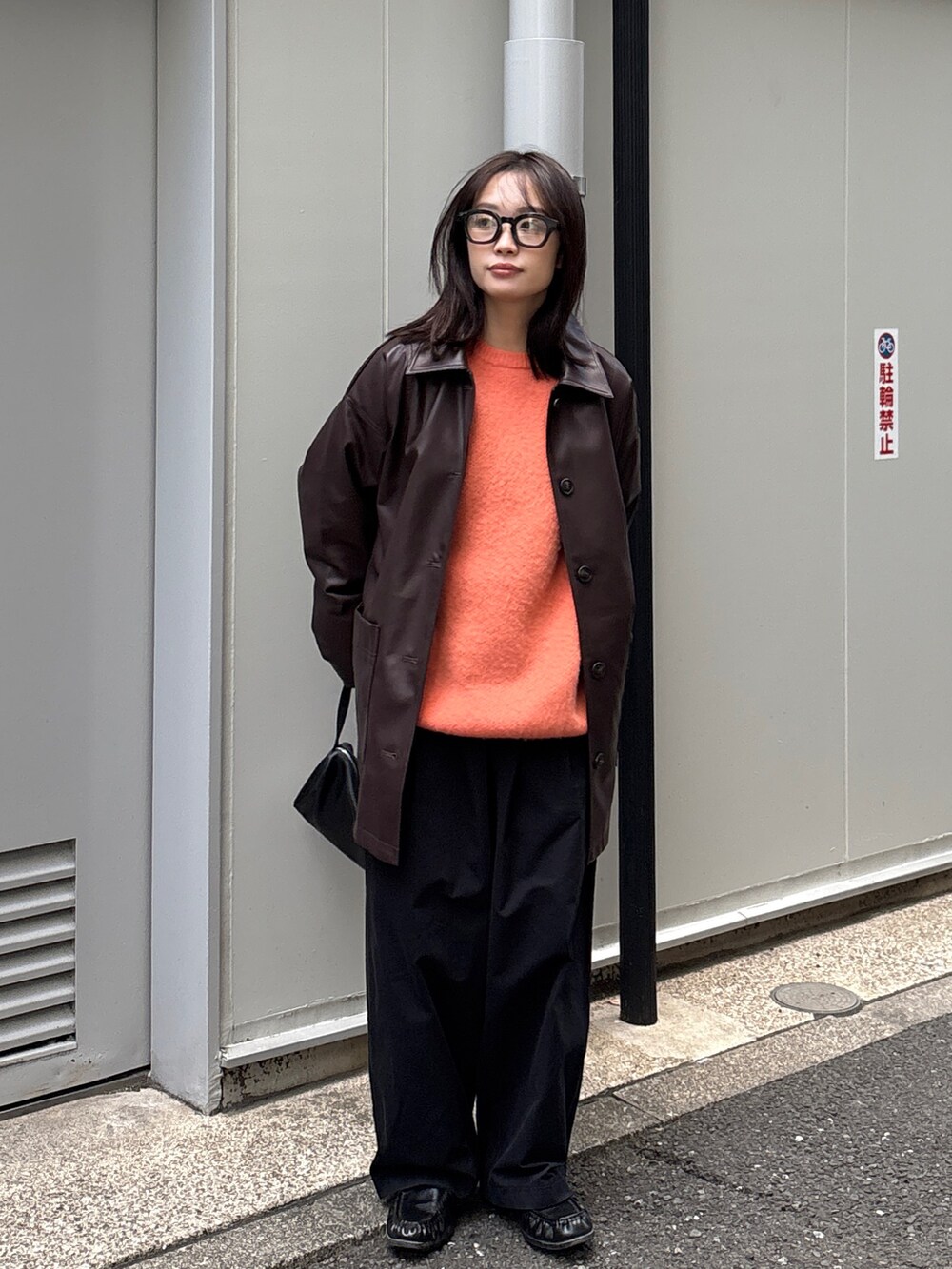 ブラウン系のカバーオール、オレンジ系のニット/セーター、ブラック系のショルダーバッグを着用したレディースの冬コーディネートの2枚目の写真