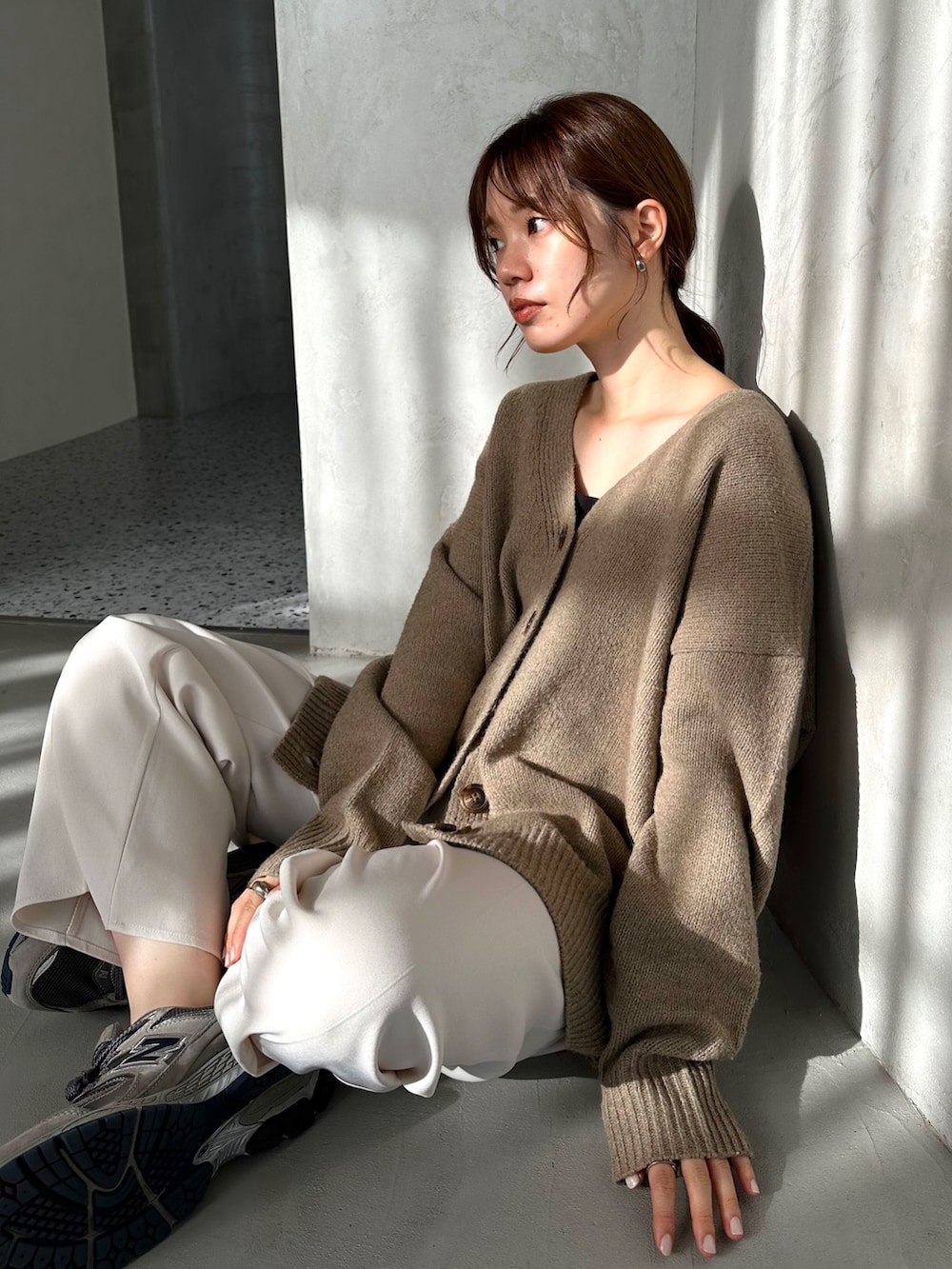 ベージュ系のカーディガン/ボレロ、ホワイト系のスラックス、グレー系のスニーカーを着用したレディースの秋コーディネートの2枚目の写真