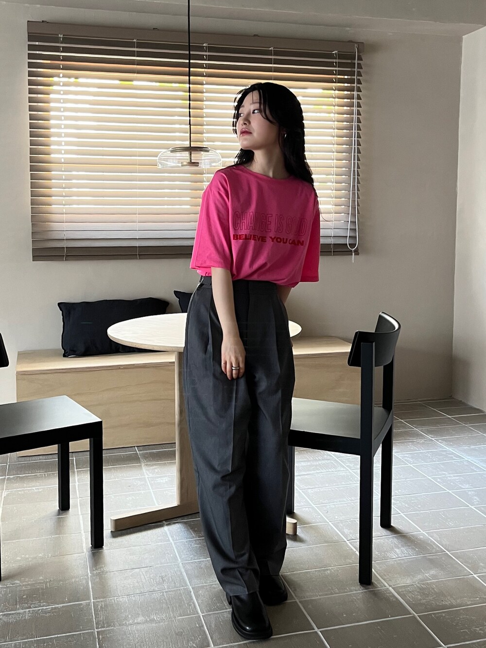 グレー系のスラックス、ピンク系のTシャツ/カットソー、ブラック系のスリッポンを着用したレディースの夏コーディネートの3枚目の写真