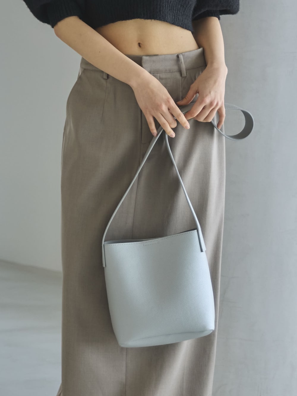 グレー系のスカート、ブラック系のニット/セーター、シルバー系のショルダーバッグを着用したレディースの夏コーディネートの6枚目の写真