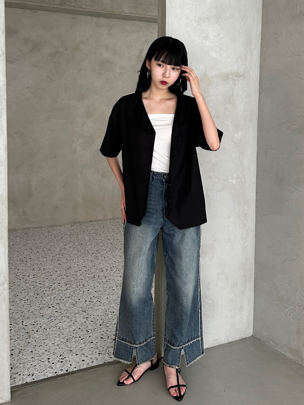 ブルー系のデニムパンツ、ブラック系のサンダル、ブラック系のノーカラージャケットを着用したレディースの夏コーディネートの2枚目の写真