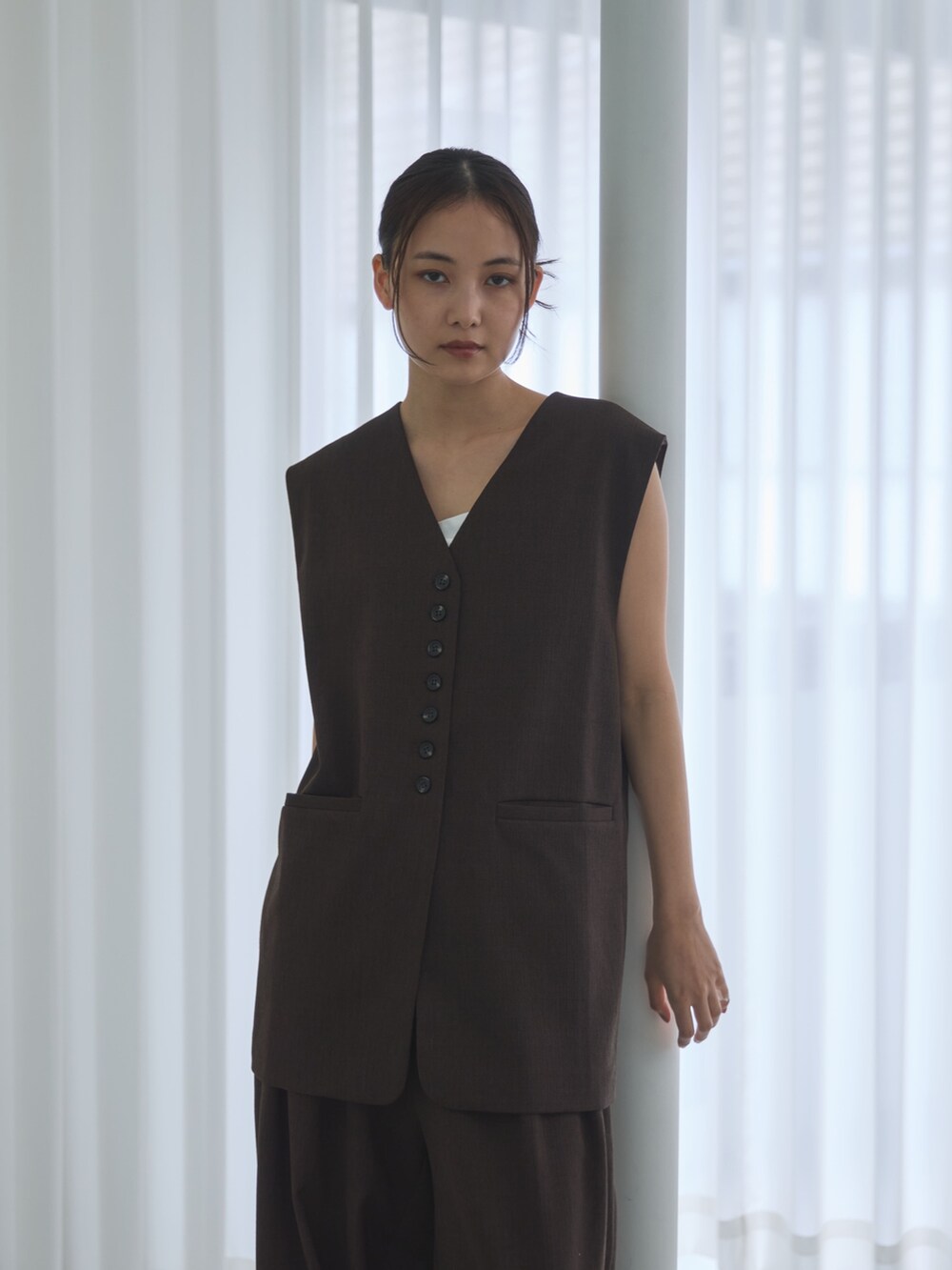 ブラウン系のベスト、ブラウン系のスラックス、ブラック系のサンダルを着用したレディースの夏コーディネートの3枚目の写真