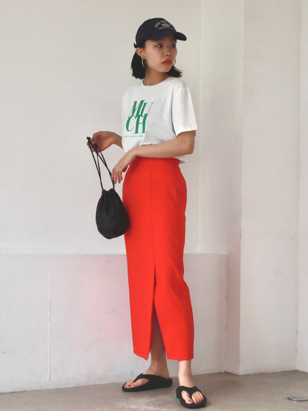 ブラック系のハンドバッグ、レッド系のスカート、ホワイト系のTシャツ/カットソーを着用したレディースの夏コーディネートの3枚目の写真