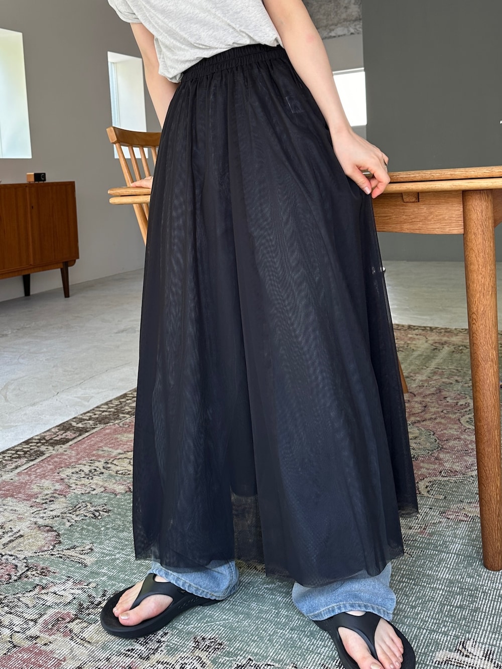 ブラック系のスカート、ブルー系のデニムパンツ、ブラック系のサンダルを着用したレディースの夏コーディネートの2枚目の写真