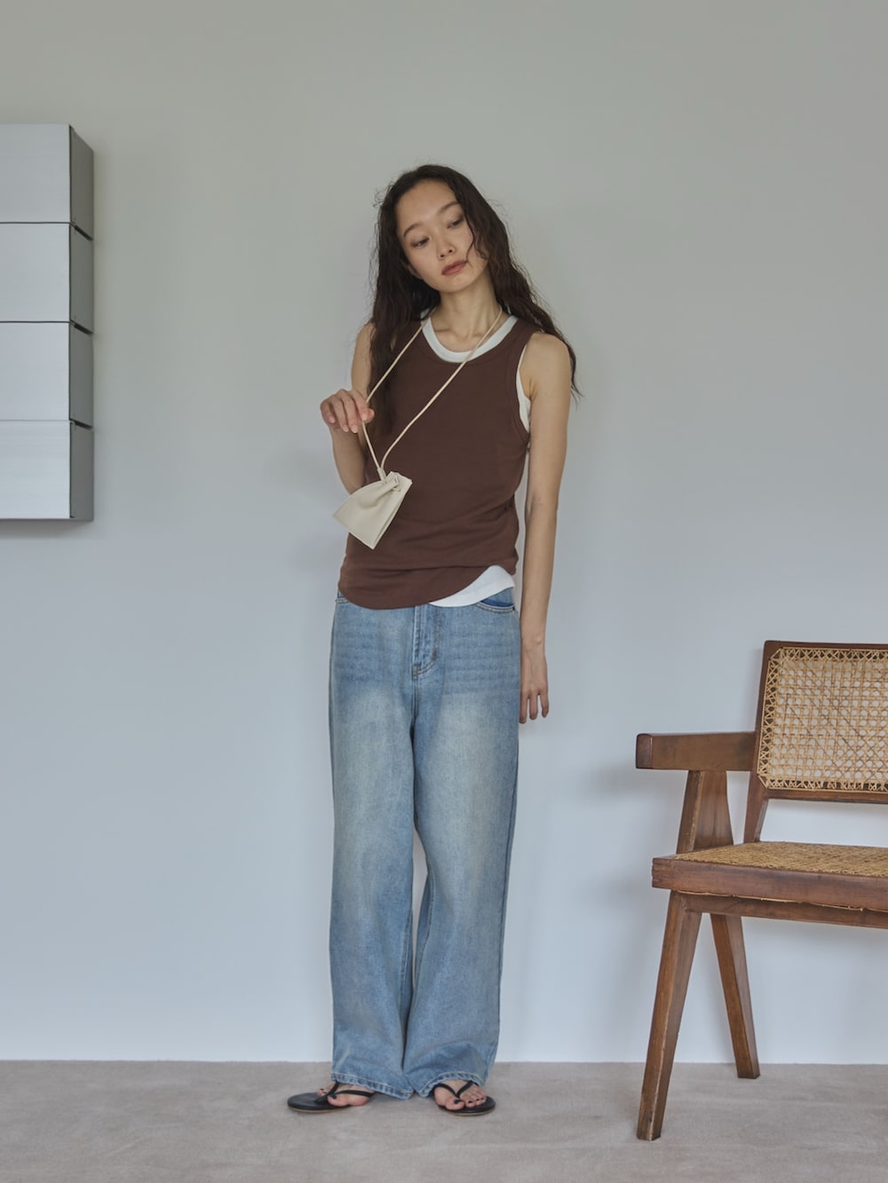 ホワイト系のタンクトップ、ブラウン系のタンクトップ、ブルー系のデニムパンツを着用したレディースの夏コーディネートの3枚目の写真