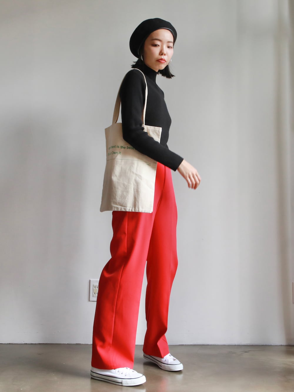 ブラック系のニット/セーター、ホワイト系のトートバッグ、ホワイト系のスニーカーを着用したレディースの冬コーディネートの2枚目の写真